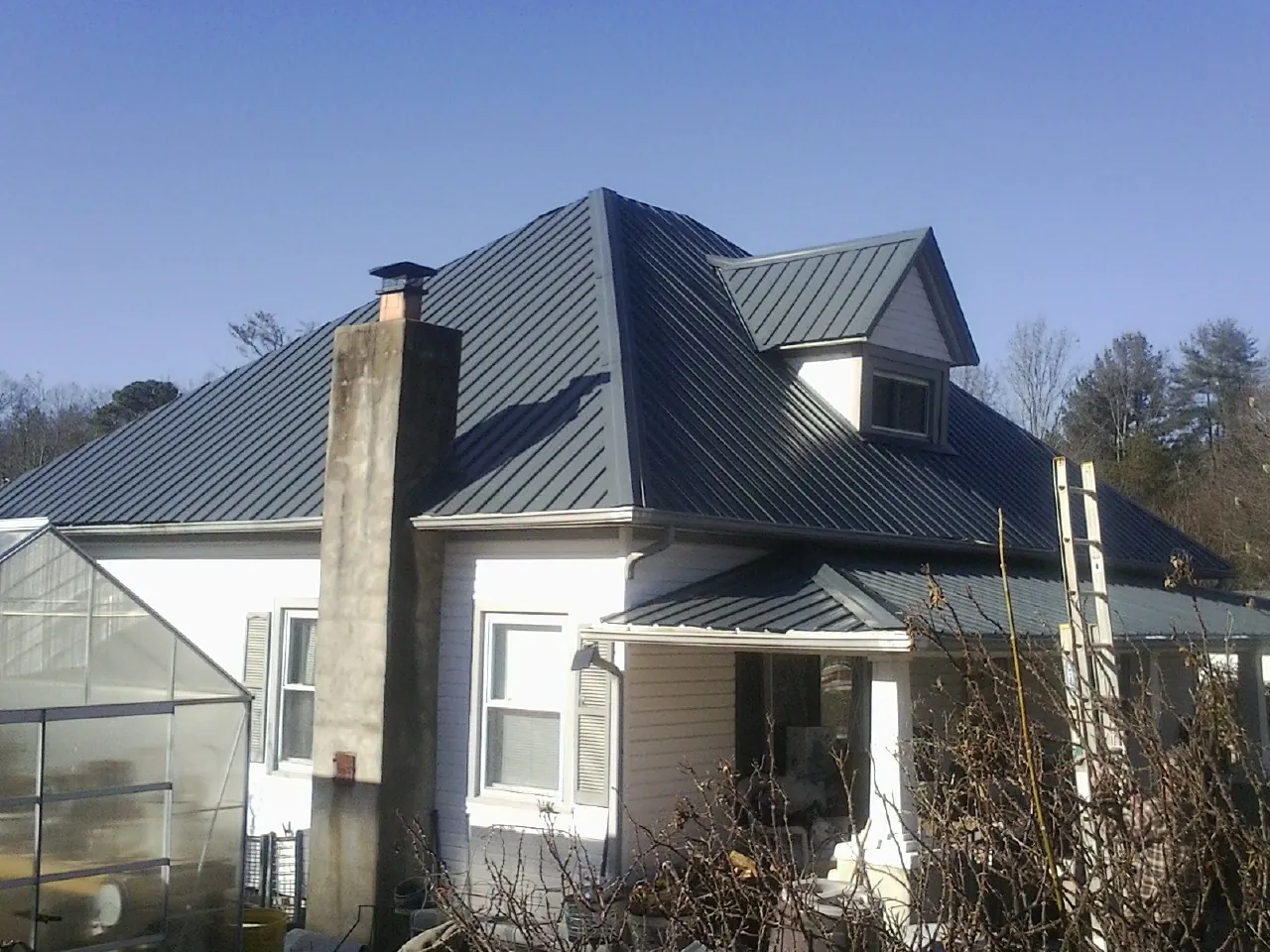 Dark blue standing seam metal roof on a white farmhouse with dormer — Slate & Tile Roof Repair by Roofing Brothers in South Hamilton