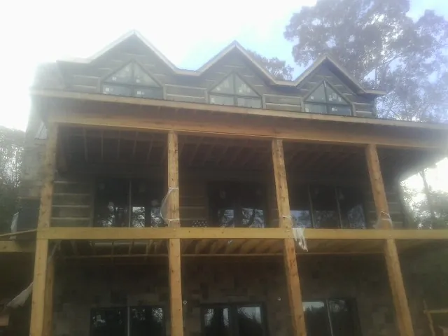 Dormers and porch framing on a large log home under construction — Roof Coating work by our crew in South Hamilton
