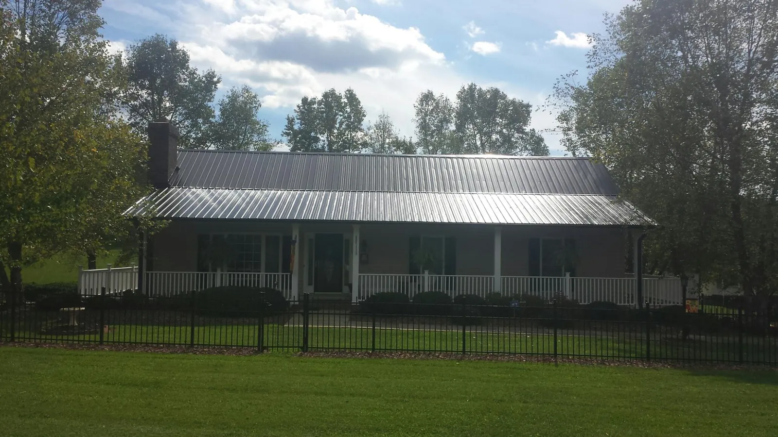Gray metal roof on a brick ranch with a full width front porch — Gutter Guard Installation work by our crew in South Hamilton