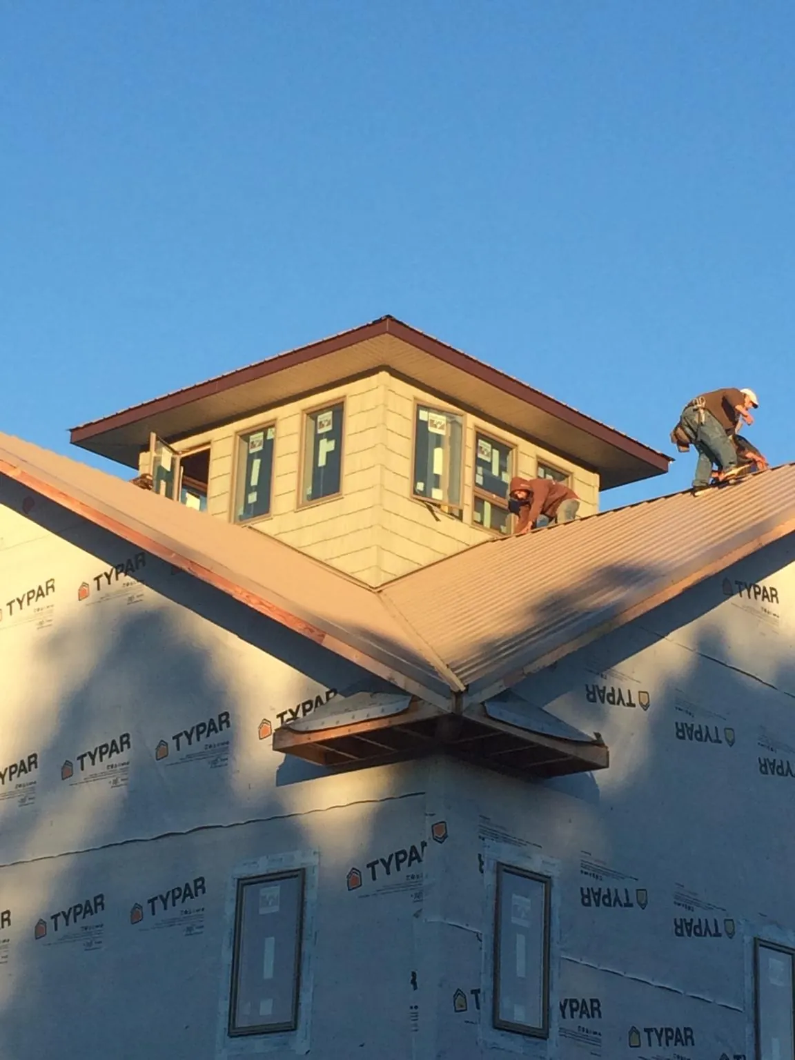 Roofers working around a rooftop cupola on a new metal roof at sunset — Roof Waterproofing in South Hamilton by Roofing Brothers